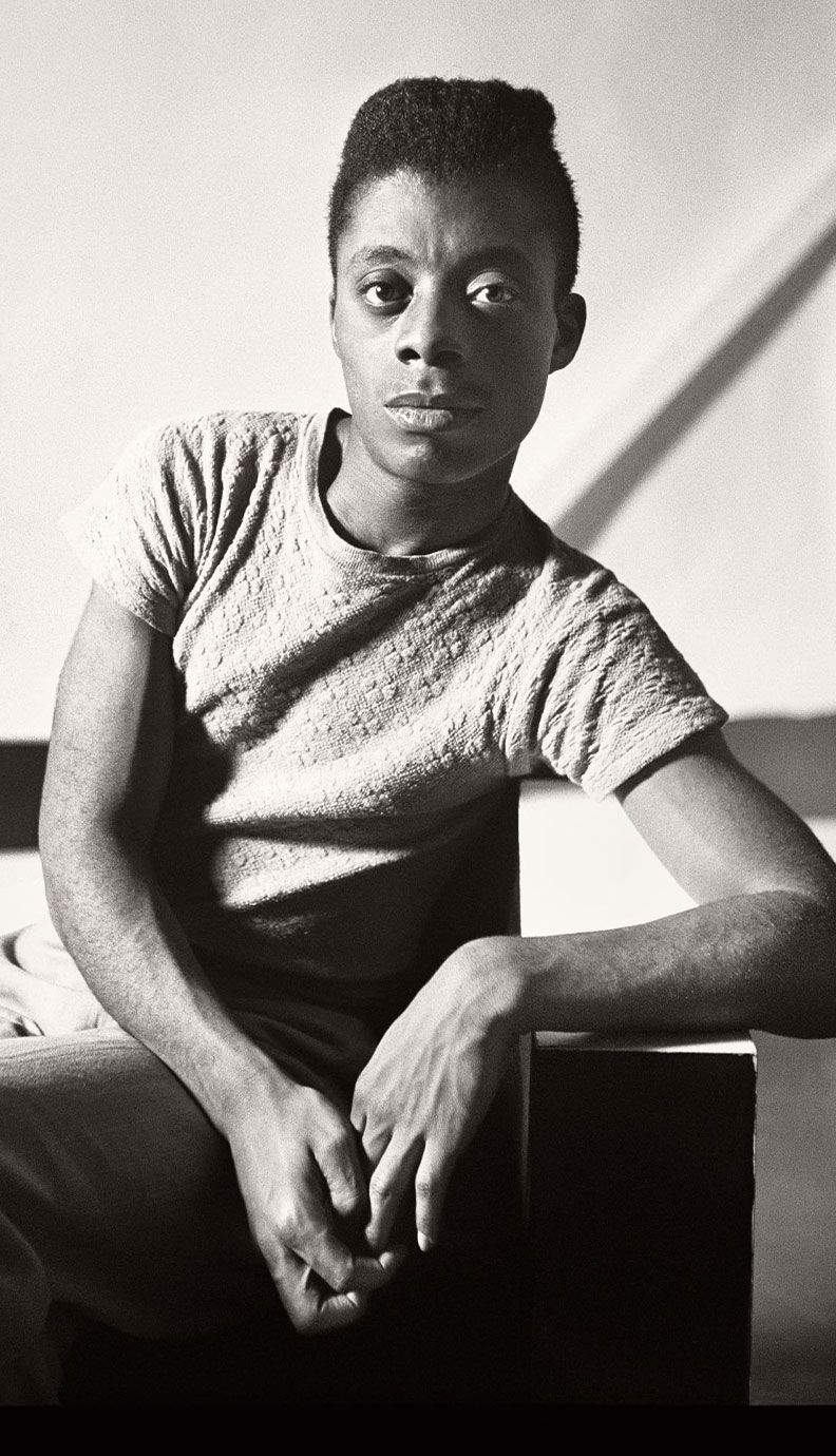 Image may contain: James Baldwin, Face, Head, Person, Photography, Portrait, Body Part, Finger, Hand, Adult, Happy, and Smile