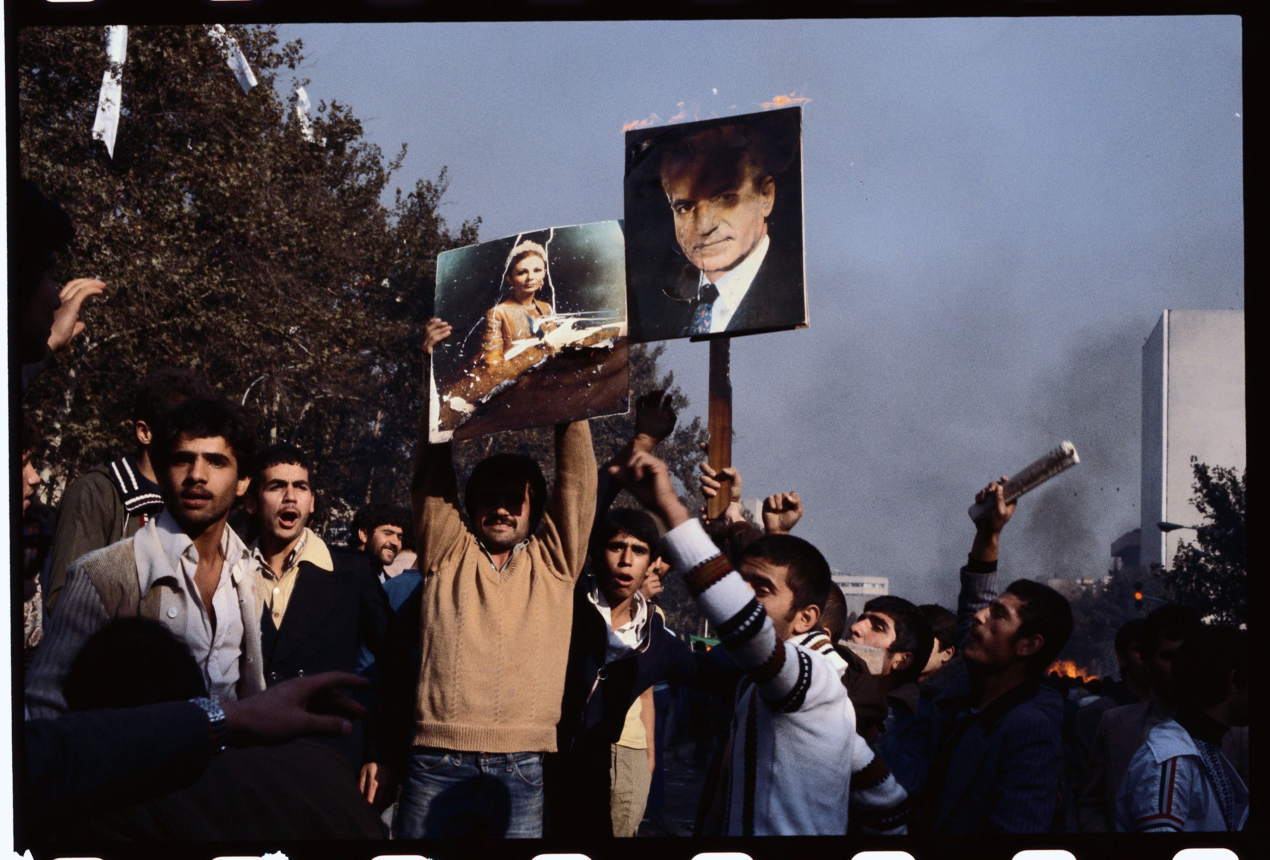 People hold posters of the Shah of Iran and his wife.