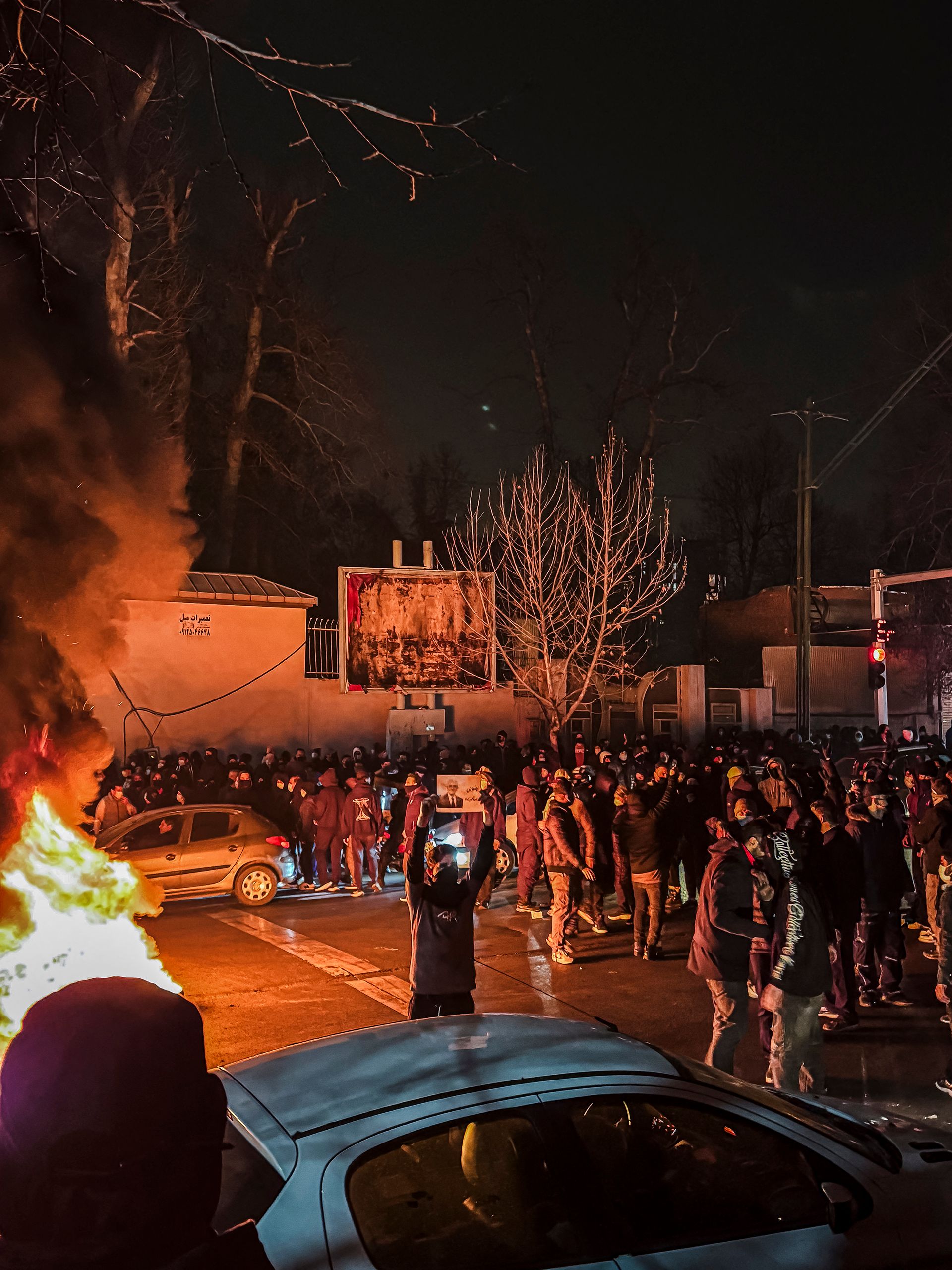 A group of protesters in Iran with flames on the left flank of the image.